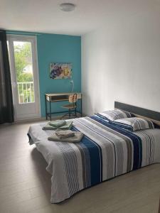 Un dormitorio con una cama con una manta a rayas. en Appartement 6 couchages environnement paisible, en Saint-Étienne-du-Rouvray