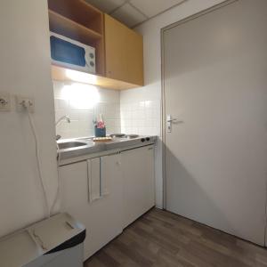 een kleine keuken met een wastafel en een deur bij Neoresid - Résidence du Parc in Reims