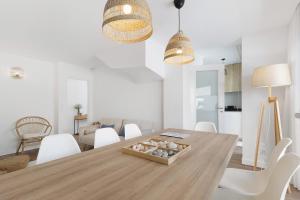 una sala da pranzo con un tavolo di legno e sedie bianche di My Beach House Esposende a Esposende