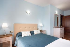 1 dormitorio con 1 cama, 2 lámparas y espejo en Home2Book Casita del Lomo, Terrace & BBQ, en La Frontera