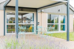 a patio with chairs and tables in front of a building at Kyriad Direct Tours Sud - Chambray Lès Tours in Chambray-lès-Tours