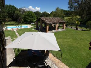 um guarda-chuva branco sentado numa cadeira ao lado de uma piscina em Scappo in Umbria, Casale Piccino em Collicello