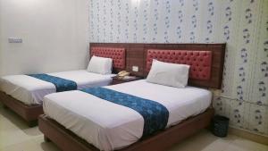 two beds in a hotel room with two bedsvisor at Hotel Rest INN in Lahore