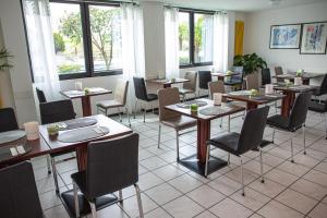jadalnia ze stołami, krzesłami i oknami w obiekcie Hotel Nessi Locarno w mieście Locarno