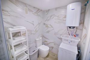 a bathroom with white marble walls and a toilet at Plazamar 6 Jose in Torre del Mar