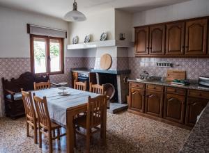 a kitchen with a table and wooden cabinets and a table and chairs at Casa Ferradal in Quintanilha