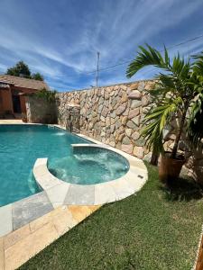 a swimming pool in front of a stone wall at Pousada Deu Praia Maragogi in Maragogi