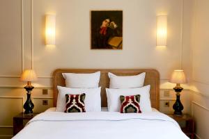 a bedroom with a bed with two lamps and a painting at H&ocirc;tel Bristol Pau in Pau