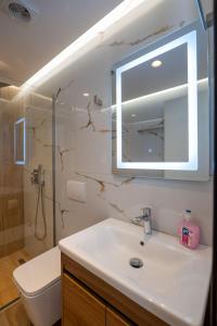 y baño con lavabo, espejo y aseo. en Fori's rooms, en Himare