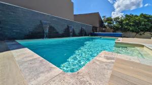 a swimming pool with blue water in front of a brick wall at Loft entre vignes et truffes - Gite en Provence Vaucluse in Valréas