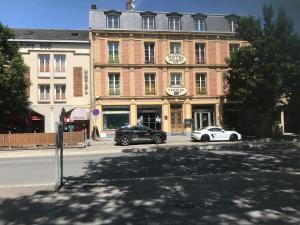 dois carros estão estacionados em frente a um edifício em Hotel Bar Restaurant Couleurs Sud em Charleville-Mézières