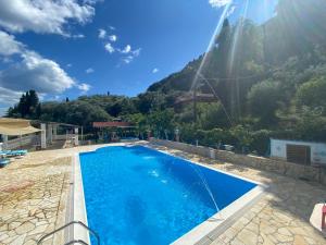 una piscina con una montagna sullo sfondo di Andromaches Holiday Apartments ad Achílleion