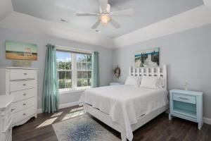 a white bedroom with a bed and a ceiling fan at Voyage Anchor in Nags Head