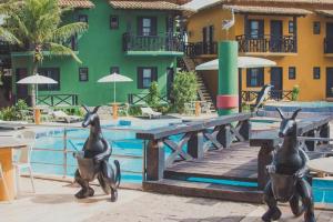 une piscine avec deux statues de pingouins en face d'un hôtel dans l'établissement Costa Marlin Hotel, à Guriri
