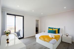 a white bedroom with a large bed with yellow and blue pillows at Pena View Villa in Santa Cruz