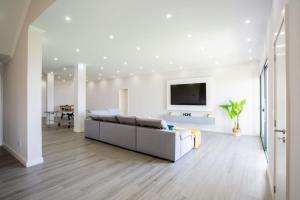 a white living room with a couch and a tv at Pena View Villa in Santa Cruz