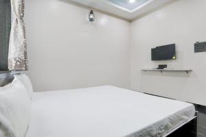a white room with a bed and a tv at OYO Hotel Raj Guest House in Akola