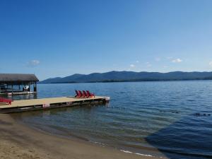 a dock with two chairs and a house on the water at The Stone Gate Resort in Lake George