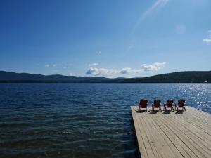 three chairs sitting on a dock over a body of water at The Stone Gate Resort in Lake George