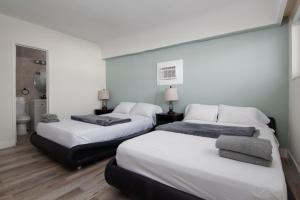 a room with three beds and a bathroom at Pousada suites in Hollywood