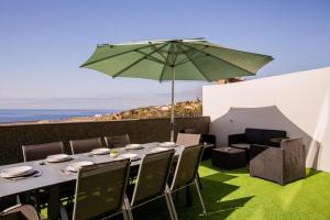 a table with a green umbrella on top of a patio at Pena View Villa in Santa Cruz