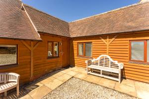 a wooden cabin with a bench on a patio at Bridge Farm Holiday Cottages in Cow Honeybourne
