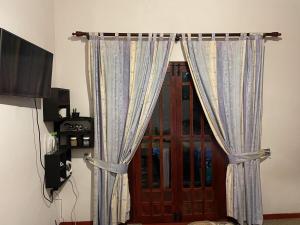 una camera con una porta con tende e una televisione di Cozy Heaven a Nuwara Eliya