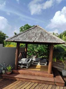 - un kiosque avec toit sur une terrasse en bois dans l'établissement Villa zen Bali piscine privée 3 chambres lotissement les hauts de la vallée d'or, à Saint-François