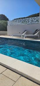 een zwembad met 2 stoelen en blauw water bij Dii Luxury Apartments in Trogir