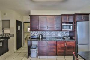 a kitchen with wooden cabinets and a stainless steel refrigerator at #16 Illovo Views in Kingsburgh
