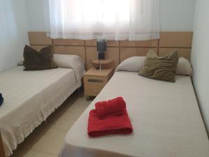 een kamer met twee bedden met een rode handdoek erop bij Holidaytorremar-84-MED021 in El Borseral +29 foto's