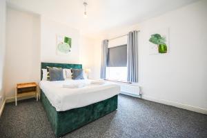 sypialnia z łóżkiem z zielonym zagłówkiem i oknem w obiekcie Sneyd House by YourStays w mieście Stoke-on-Trent