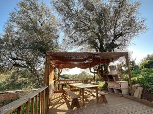 a wooden deck with a picnic table and a canopy at Casa do Baloiço do Pitagudo in Maceira