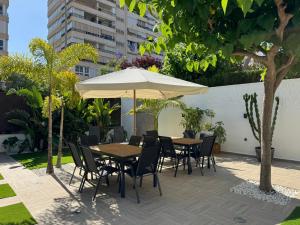 a patio with a table and chairs and an umbrella at La Casita Beach Garden By Sunset in Alicante