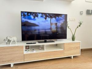 a large flat screen tv on a white entertainment center at La Casita Beach Garden By Sunset in Alicante