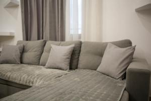 - un canapé avec des oreillers dans une chambre avec une fenêtre dans l'établissement Green-Garden Apartmets, à Saranda