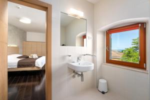 ein Bad mit einem Waschbecken, einem Bett und einem Spiegel in der Unterkunft Boutique Wrungel in Vrsar