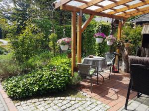 a patio with a pergola and chairs and plants at Ferienwohnung Kerstin in Strackholt in Großefehn 
