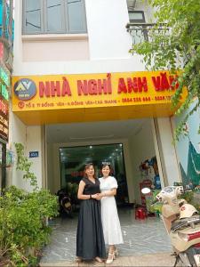 Deux femmes sont debout devant un bâtiment dans l'établissement NHÀ NGHỈ ANH VĂN, à Dong Van