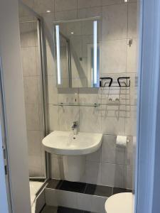 Baño blanco con lavabo y espejo en Hotel König Humbert, en Erlangen