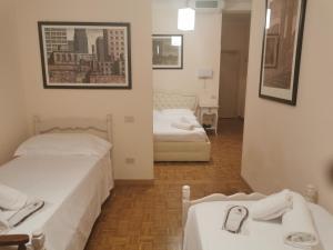 duas camas num pequeno quarto com lençóis brancos em Hotel Villa Quiete em Montecassiano
