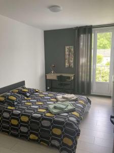 Un dormitorio con una cama y un escritorio y una ventana. en Appartement 6 couchages environnement paisible, en Saint-Étienne-du-Rouvray