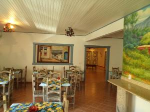 uma sala de jantar com mesas e cadeiras e um quadro em Pousada Serenna Centro em Tiradentes