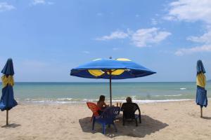 two people sitting at a table under an umbrella on the beach at Hotel Juanmar in Juan de Acosta