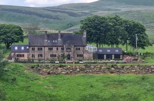 an old stone house in the middle of a field at Oakenclough Hall in Macclesfield