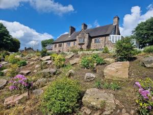 an old house on top of a hill with flowers at Oakenclough Hall in Macclesfield