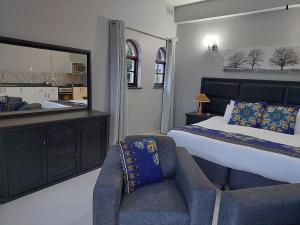 Fairway Guest Lodge في مارغيت: غرفة نوم بسرير وكرسي ومرآة