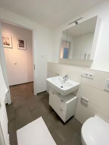 uma casa de banho branca com um lavatório e um WC em helloYOU Apartments em Ingelheim am Rhein