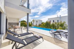 Un patio con tumbonas y una piscina. en Villa Kalu 1, en Krnica
