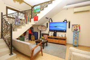a living room with a staircase and a tv at The Villa Hostel Abu Dhabi in Abu Dhabi